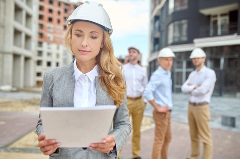 Eine Frau auf der Baustelle wird von drei Männern beobachtet: Die Branche ist männerdominiert und Frauen gegenüber besteht so manches Vorurteil.