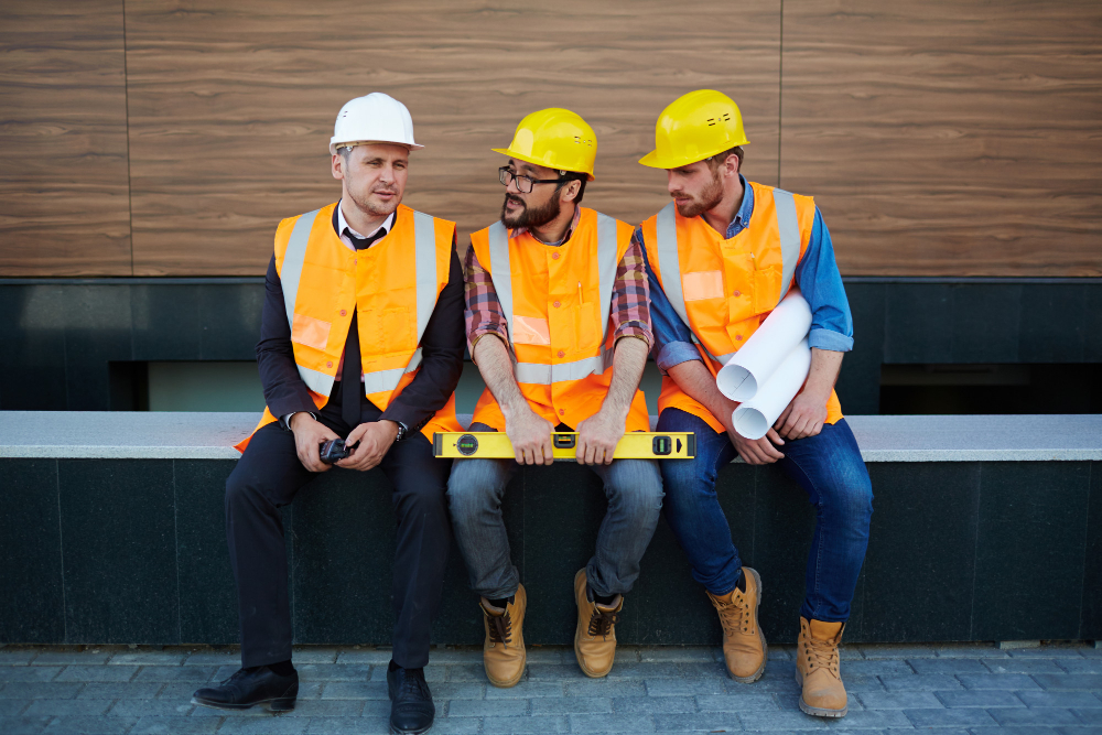 Baufachkräfte sitzen auf einer Bank: Der Mangel an qualifizierten Arbeitnehmern im Baugewerbe erfordert besondere Strategien.